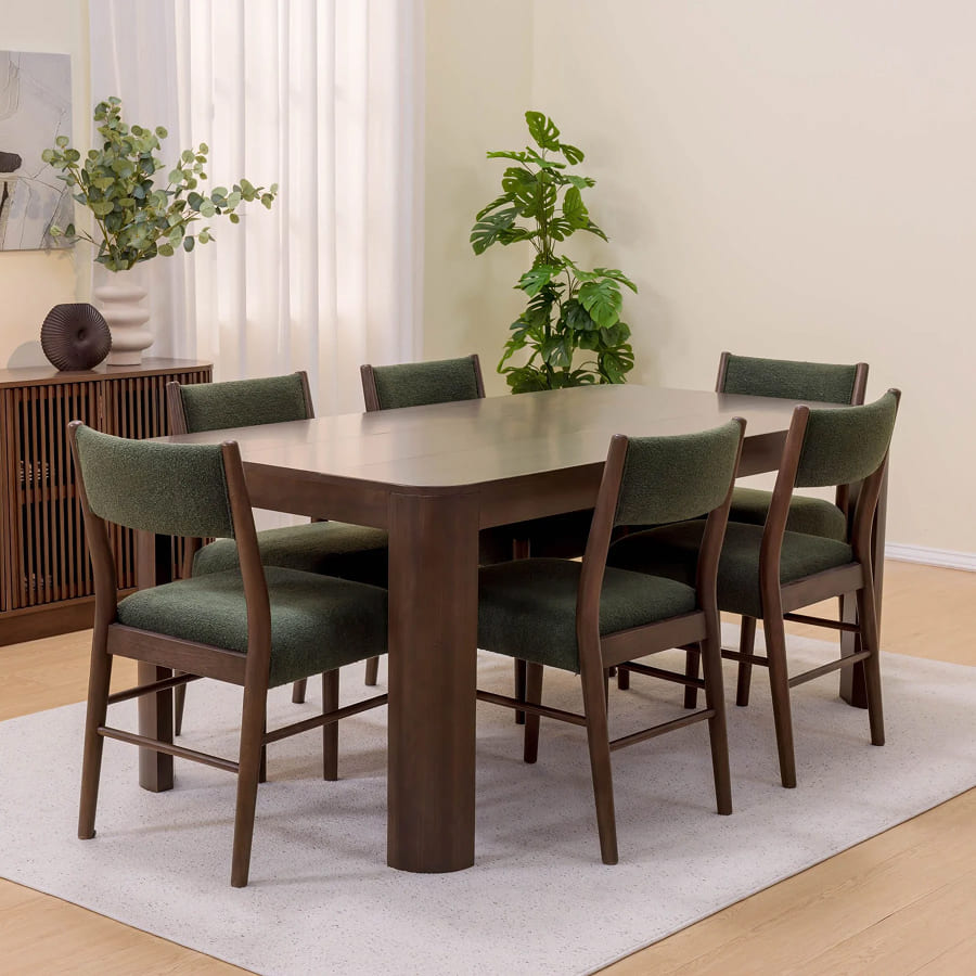 Modern wooden dining table set with green upholstered chairs in a bright dining room.