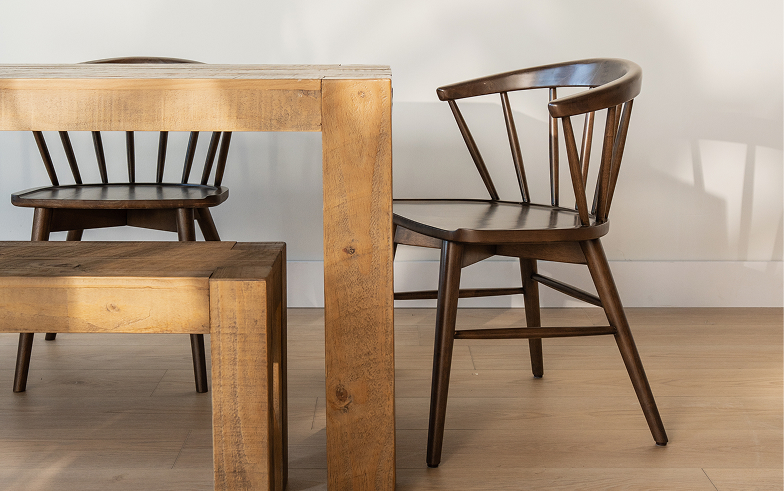 A wooden dining table with a matching dining bench and two darker wood dining chairs.