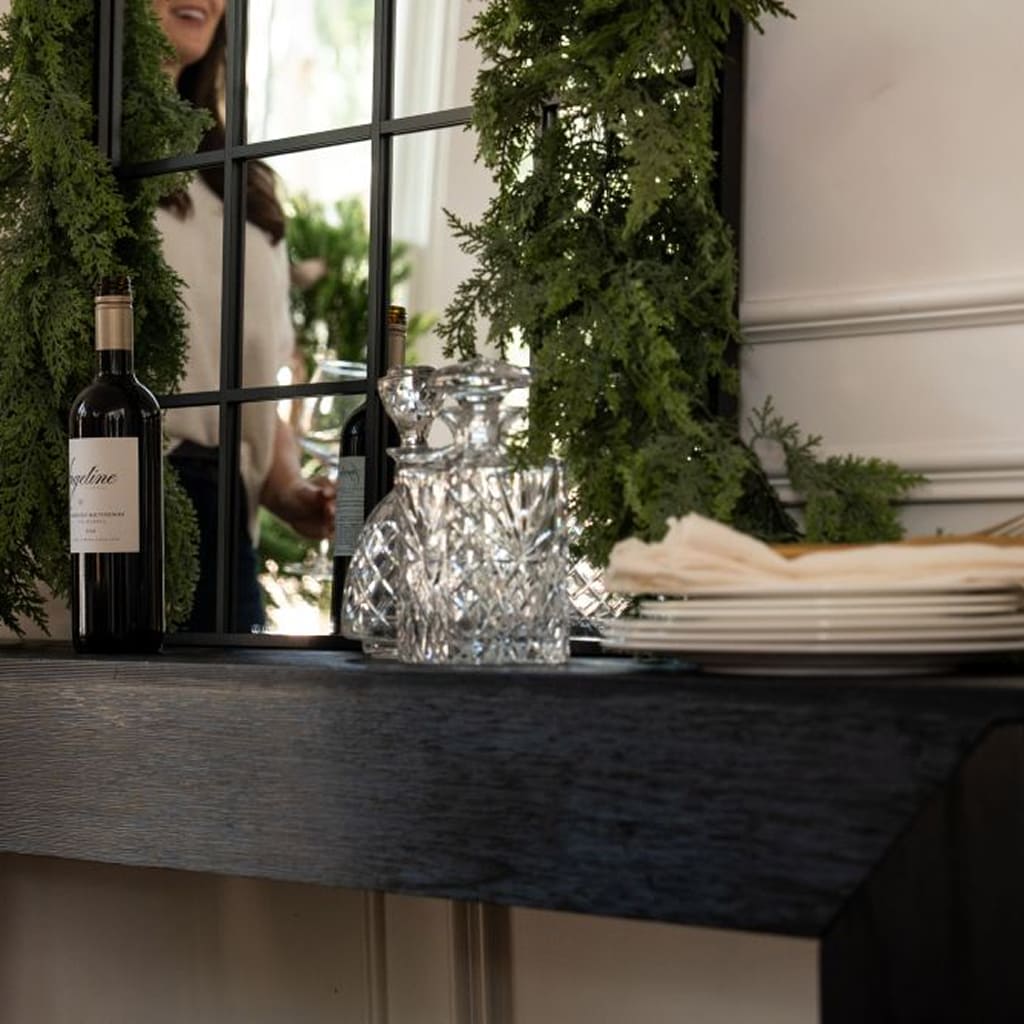 Table setting with wine bottle, crystal vase, and plates in a decorated room.