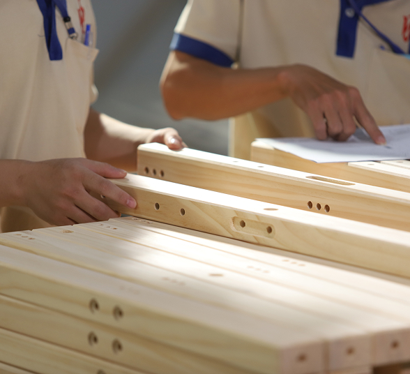Two people sorting through stacked pieces of wooden furniture.