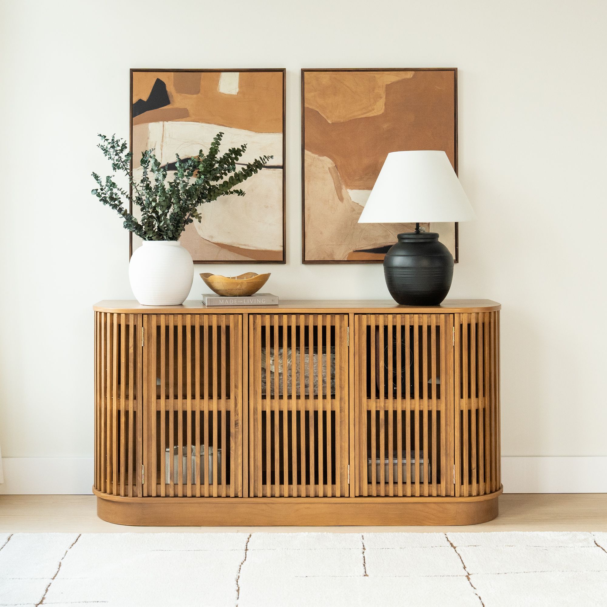 Mid-century modern wooden sideboard with botanical decor and abstract art frames.