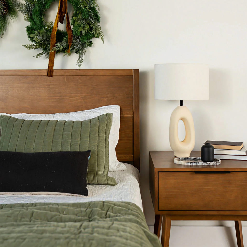 Holiday decorated bedroom with modern lamp and solid wood bedframe plus nightstand set.