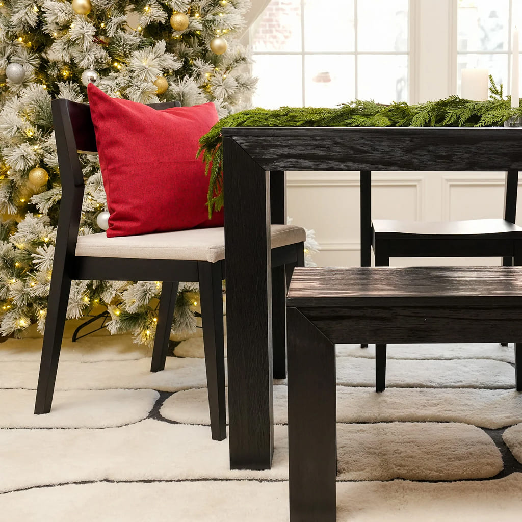 Black modern dining table set with cream upholstered chair set in a holiday decorated dining room.