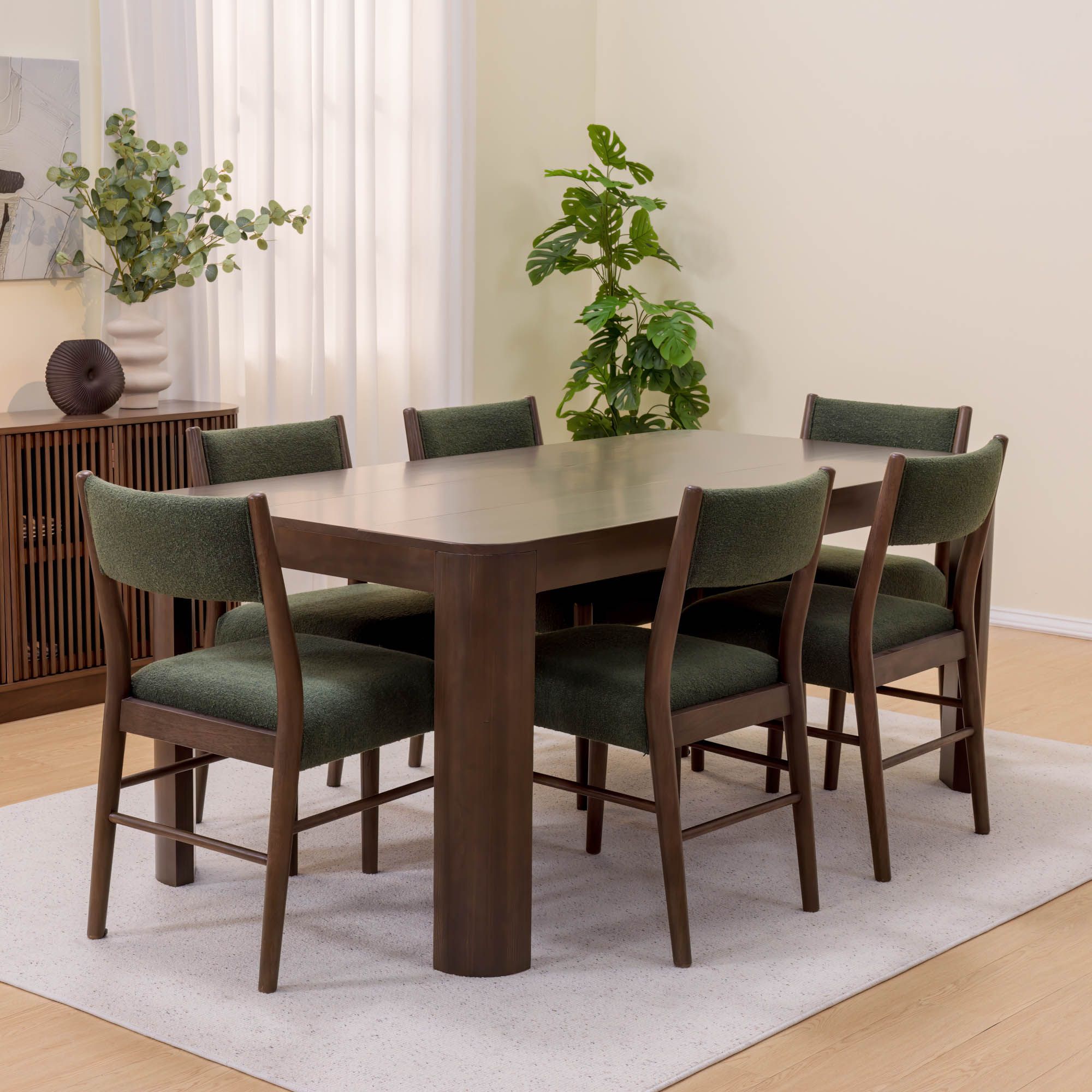 Modern wooden dining table set with green upholstered chairs in a bright dining room.