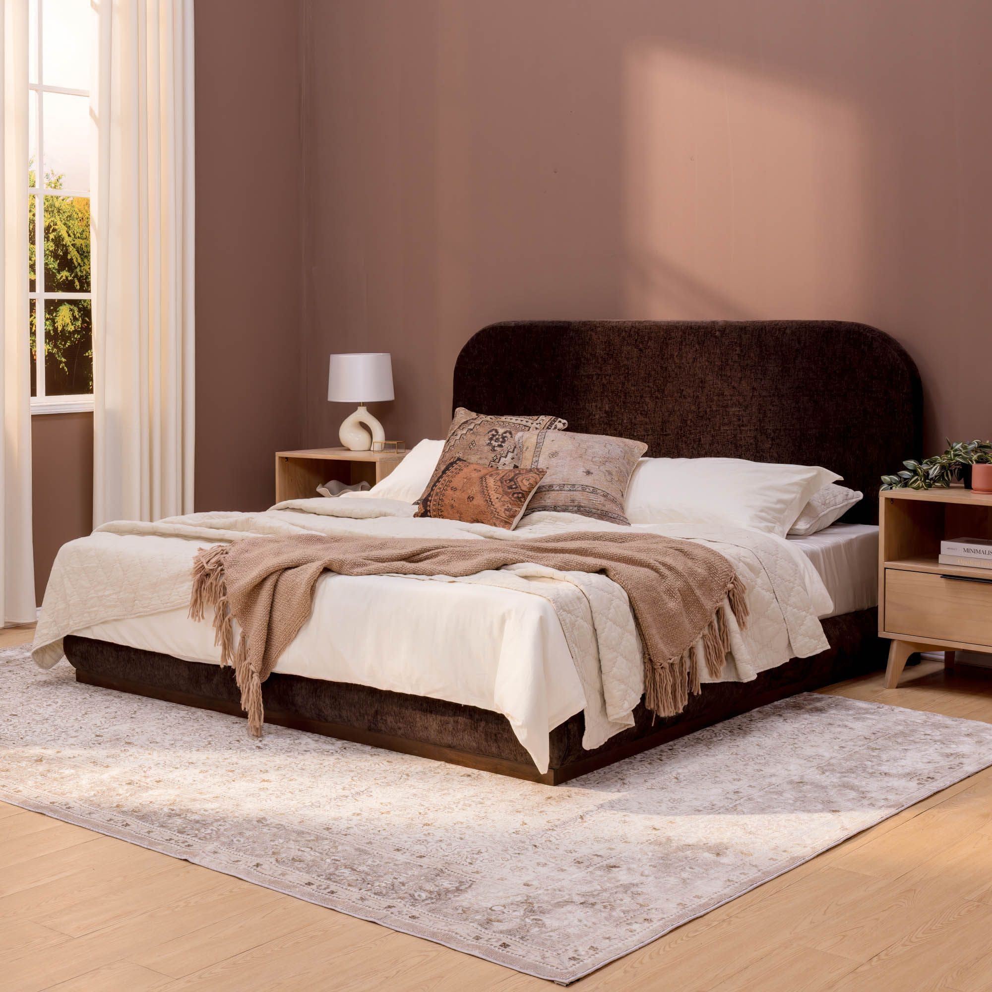 Modern bedroom interior with stylish brown bed, beige linens, and decorative pillows in a cozy, well-lit space.