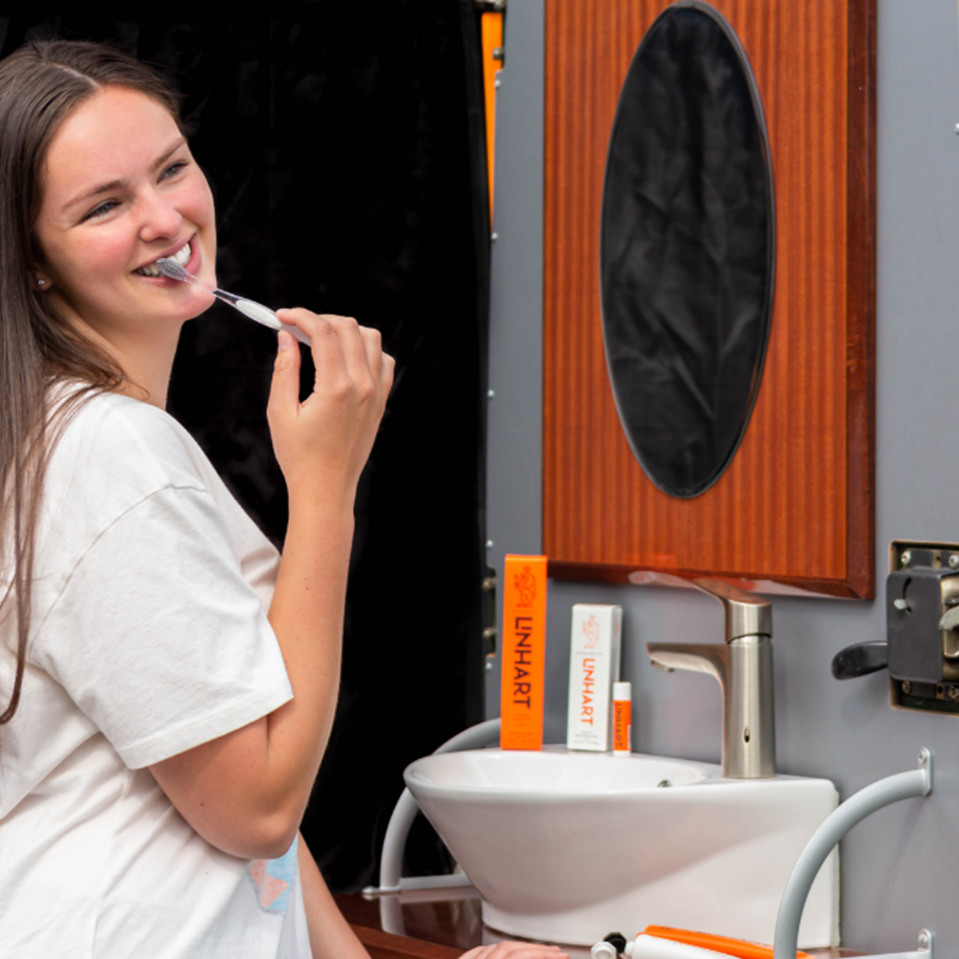 Person brushing teeth in front of a sink with a mirror.