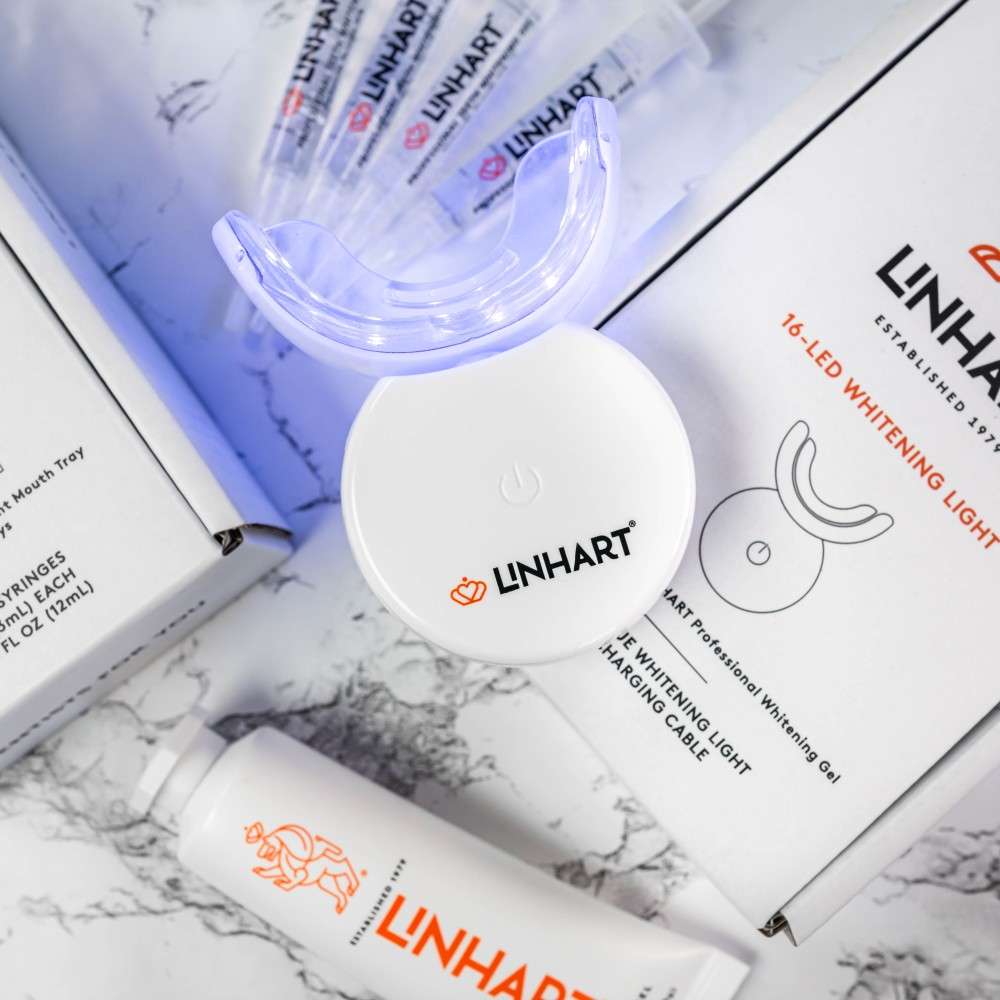 Linhart LED teeth whitening kit with mouth trays and syringes on a marble surface.