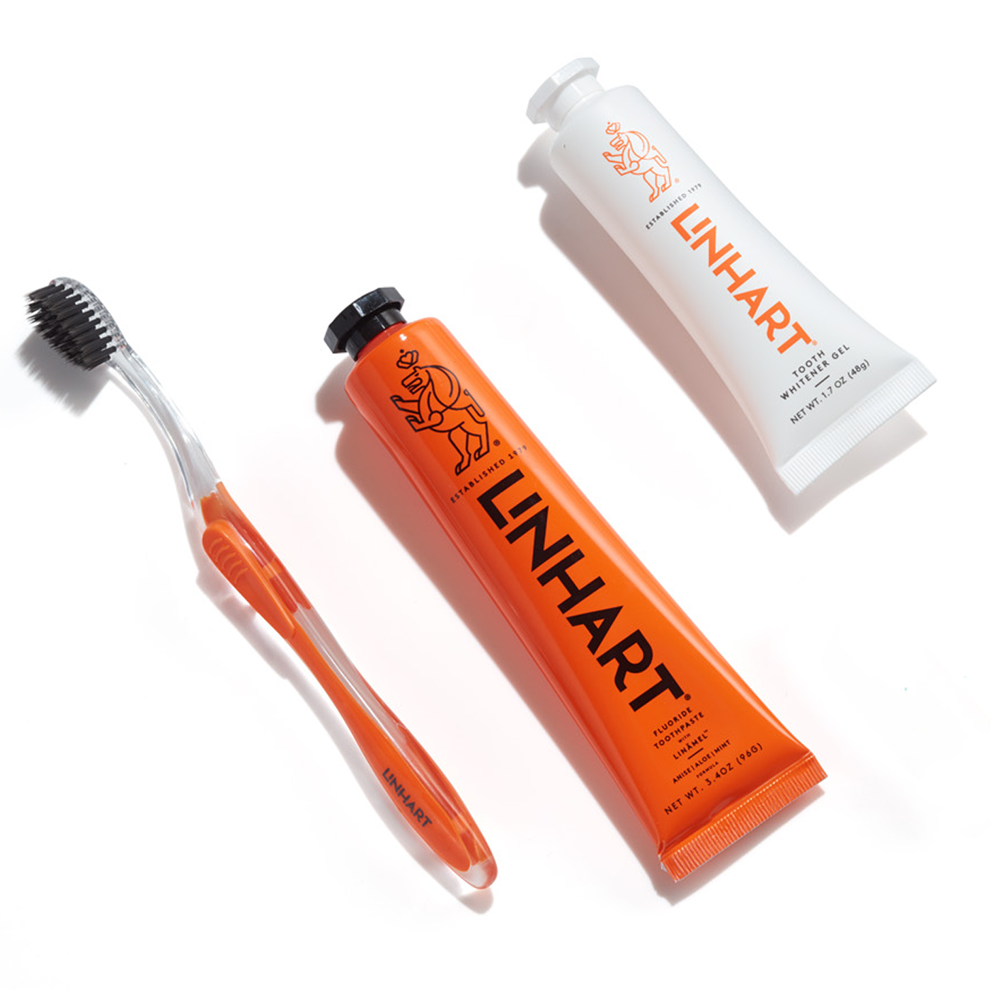 Orange toothbrush and toothpaste tubes labeled 'LINHART' on a white background.