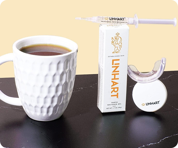 Mug of coffee next to tooth whitening gel and LED device.