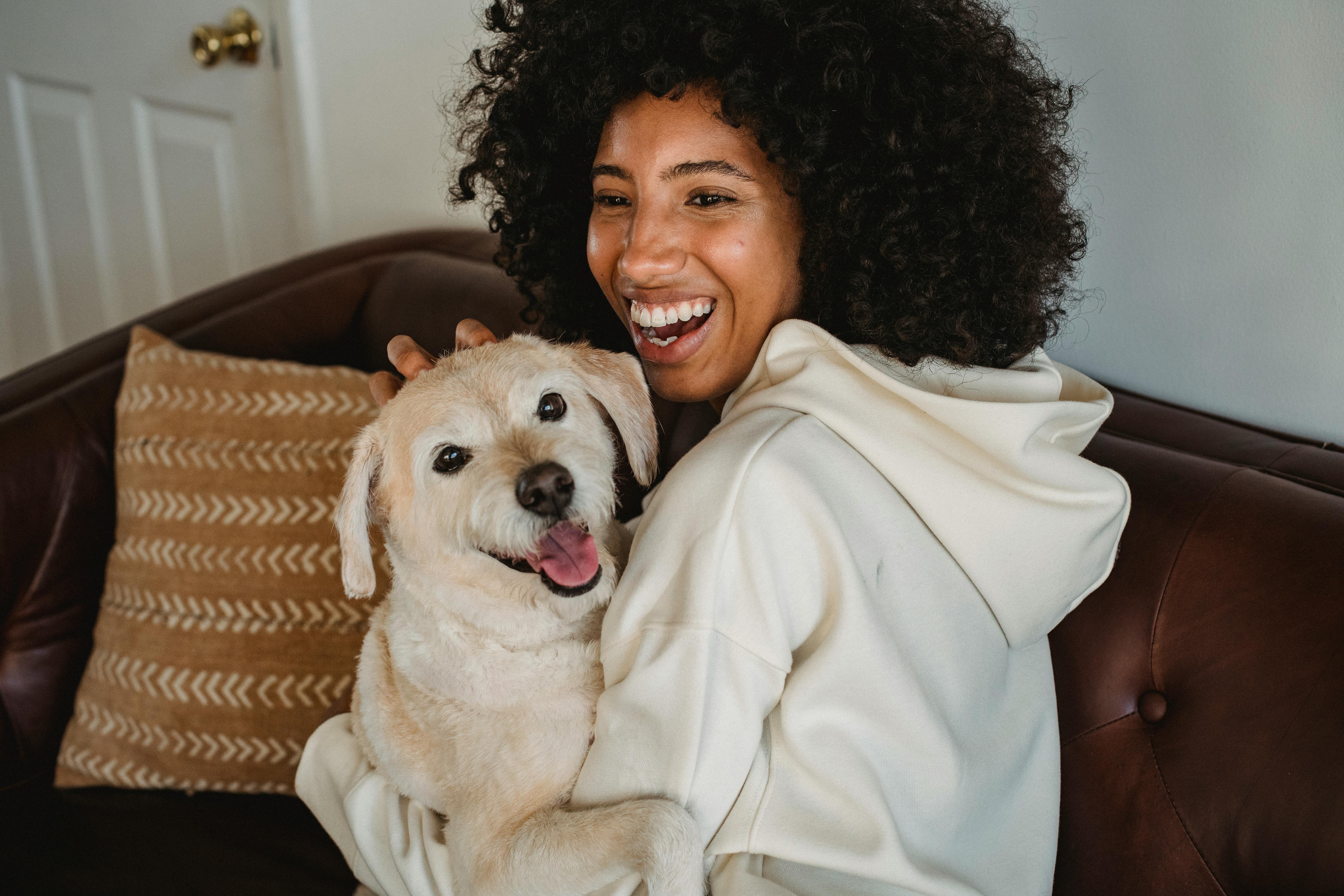 Person smiling while holding a happy dog on a couch.