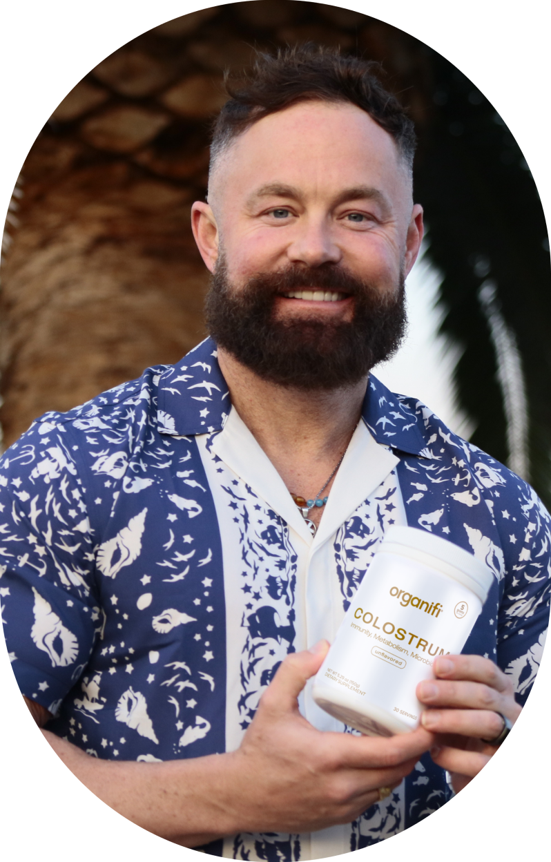 Man in patterned shirt holding a container of Organifi Colostrum.