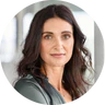 A circular headshot of a woman with long dark hair looking towards the camera.