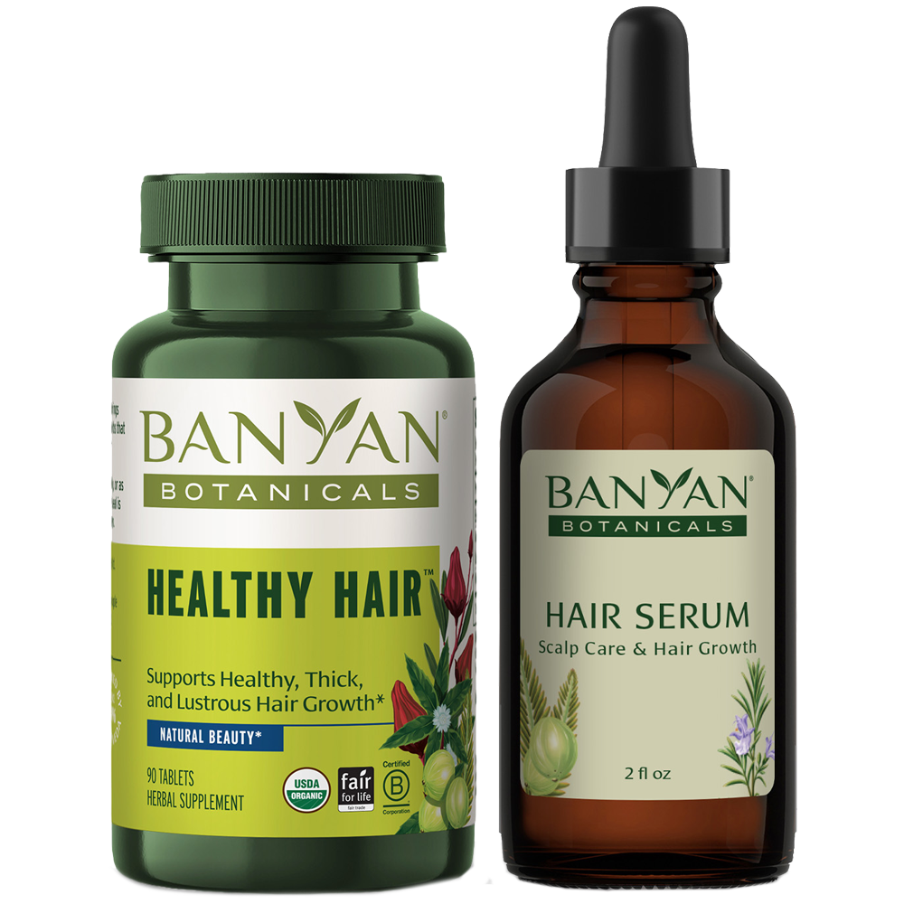A bottle of Banyan Botanicals Healthy Hair tablets next to a dropper bottle of their Hair Serum.