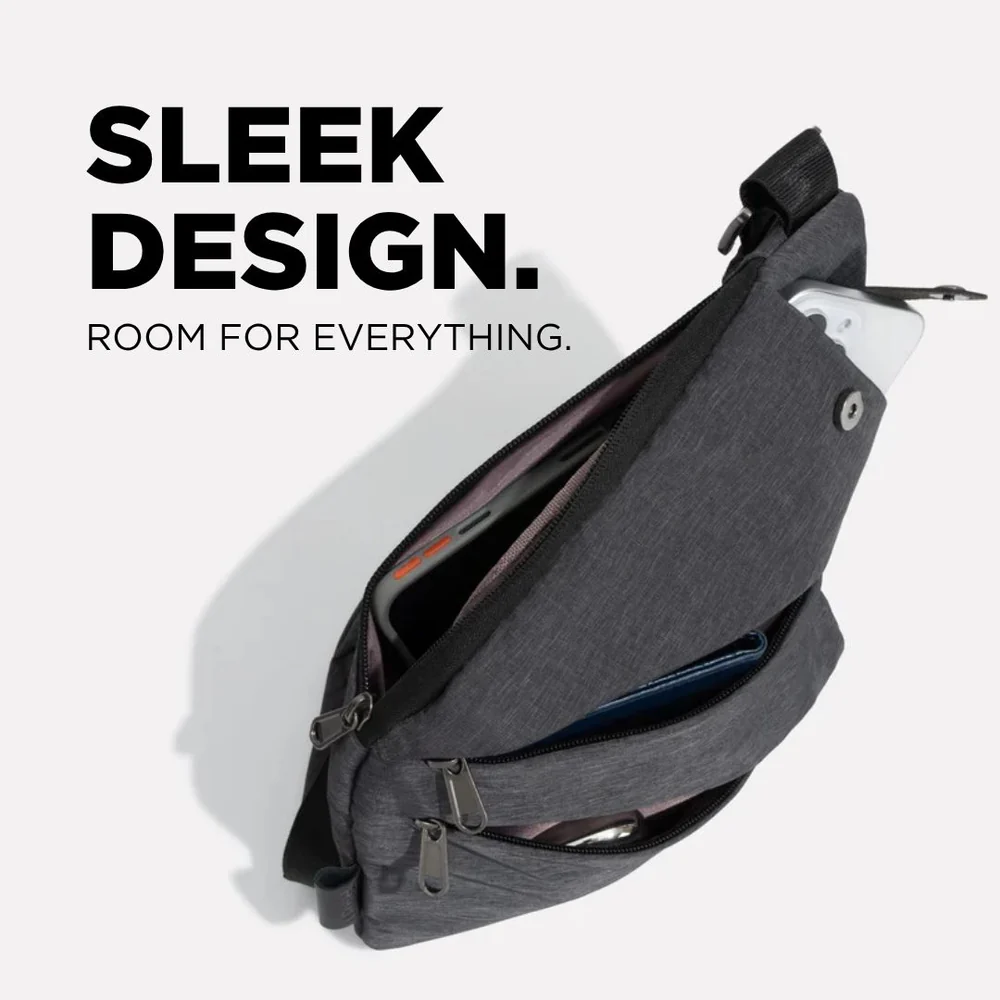 A dark gray crossbody bag is open, showing multiple pockets containing a phone, wallet, and other items.
