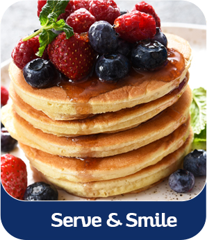 A stack of pancakes is topped with syrup and fresh berries, with a banner reading 'Serve & Smile'.