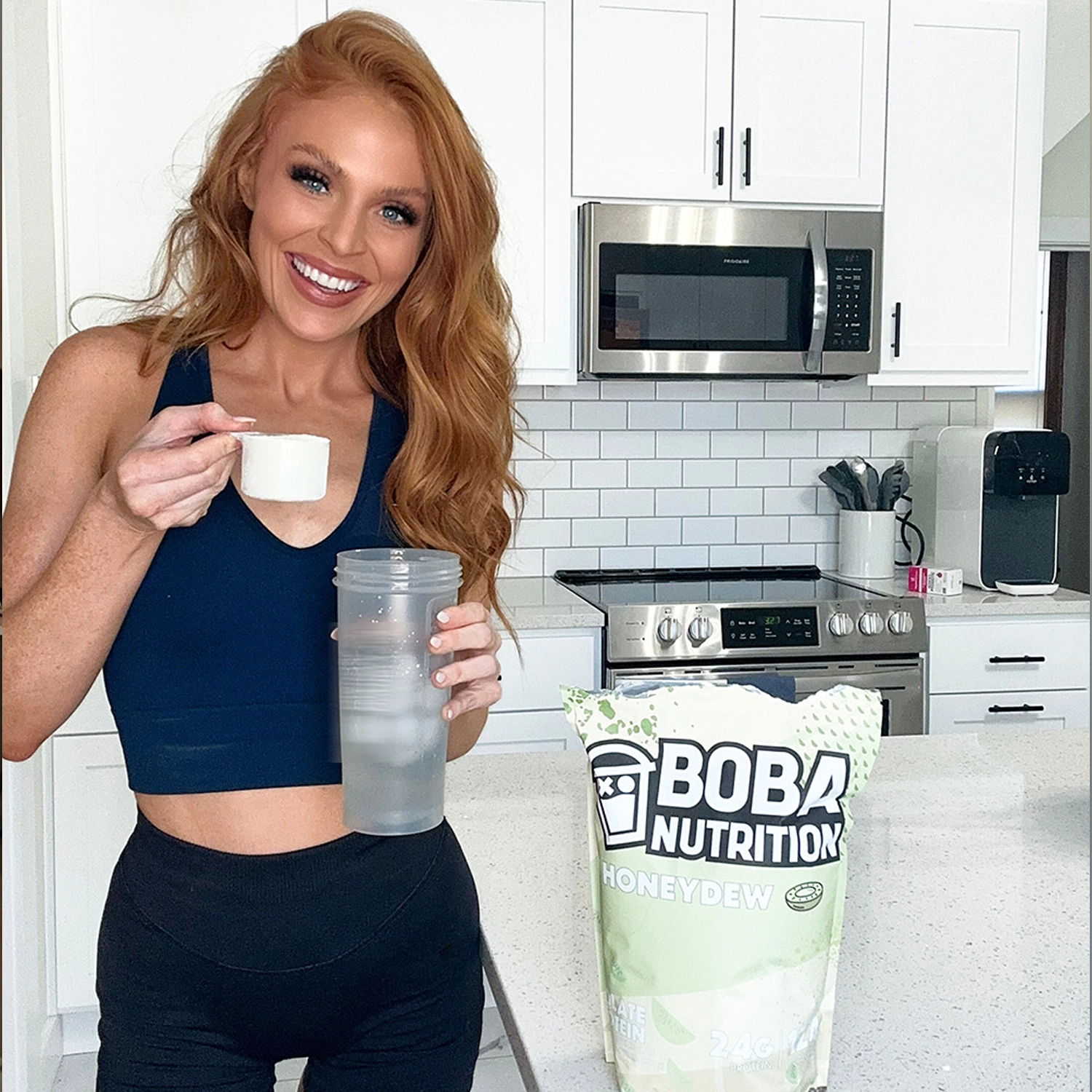 Woman preparing a protein shake in a modern kitchen.