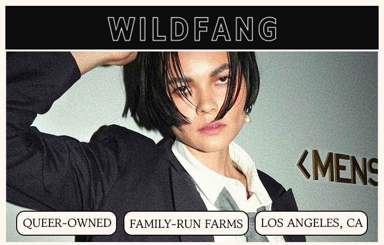 A person with short dark hair in a blazer poses for a Wildfang advertisement.
