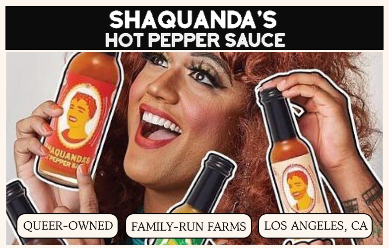 A person in drag makeup smiles while holding bottles of Shaquanda's Hot Pepper Sauce.