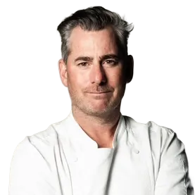 Person in a chef's coat with crossed arms, neutral expression.