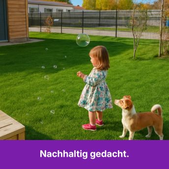 A young girl and a dog play with soap bubbles on a lush green lawn.