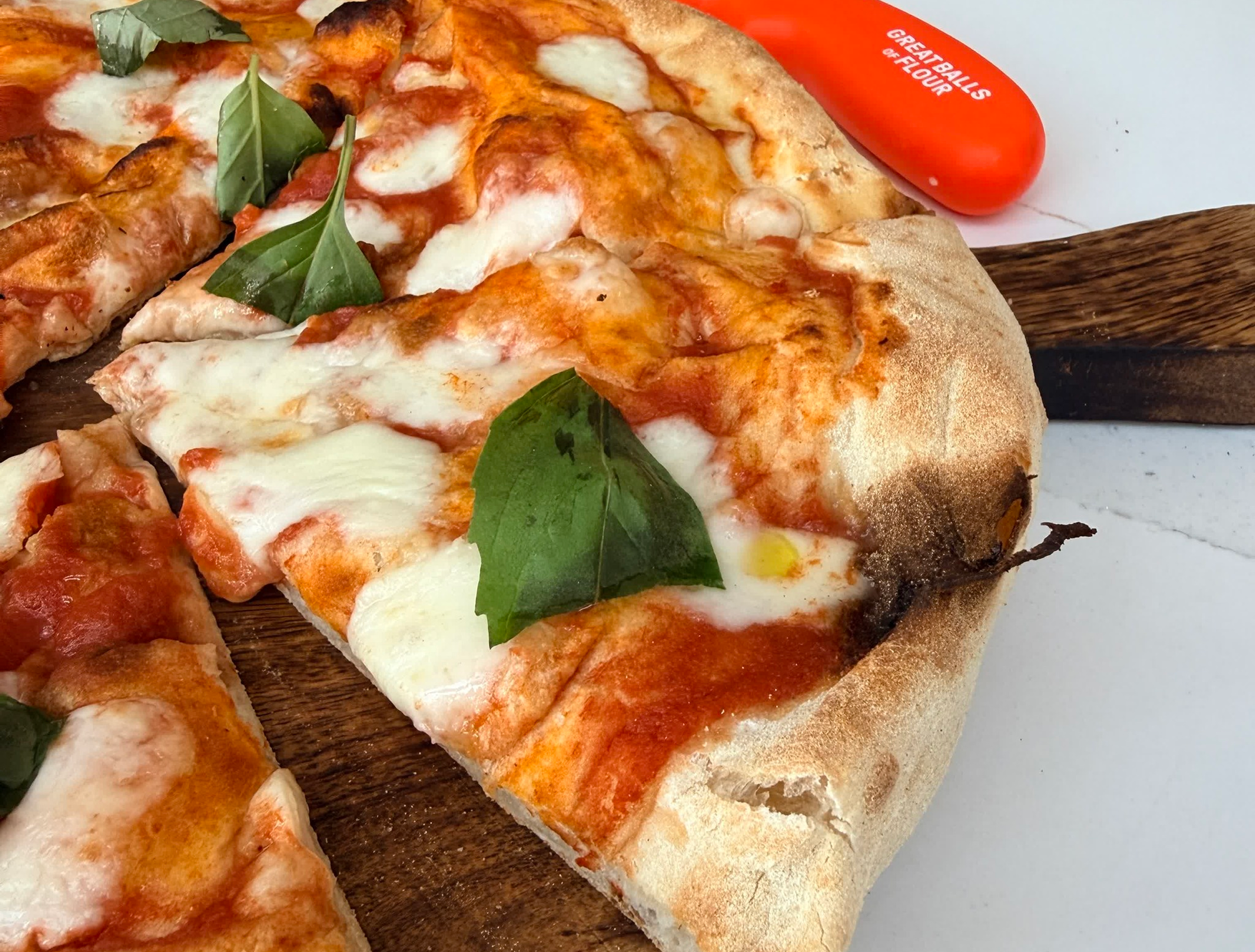 A close-up of a sliced Neapolitan-style pizza with tomato sauce, fresh mozzarella, and basil leaves.