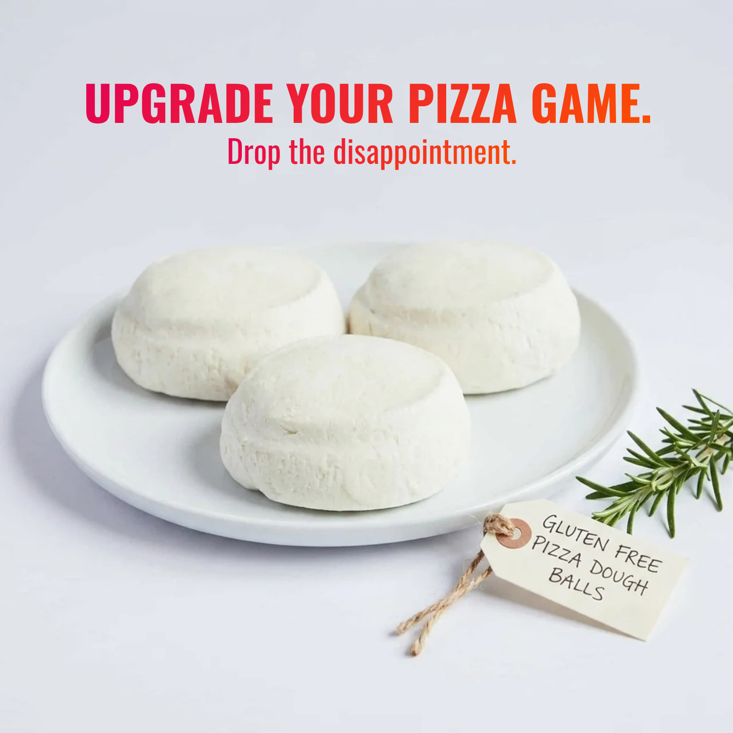 Three gluten-free pizza dough balls on a white plate with a sprig of rosemary and a tag.