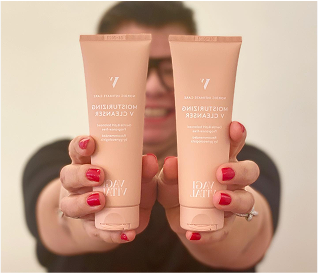 Person holding two tubes of moisturizing V cleanser with pink caps.