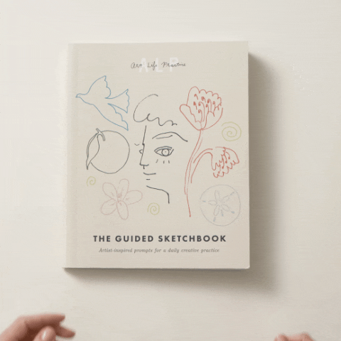Hands flipping through a sketchbook with abstract line drawings on the cover.