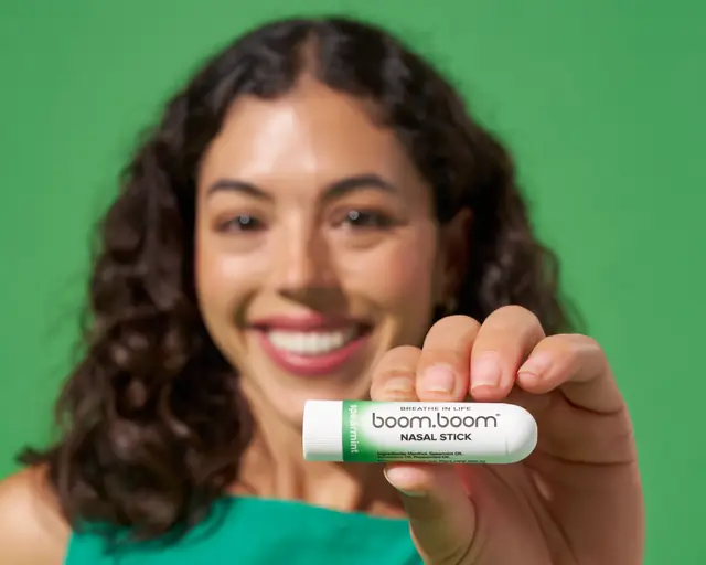 Woman holding up a Spearmint BoomBoom Nasal Stick