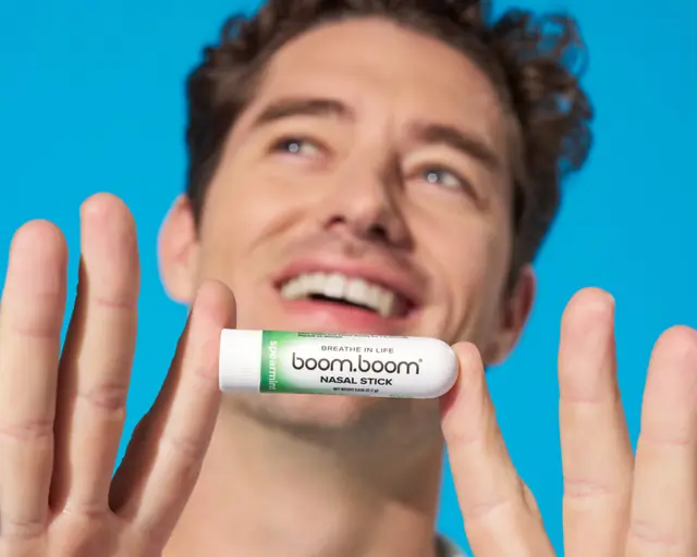 Smiling man holding up a Mint BoomBoom Nasal Stick