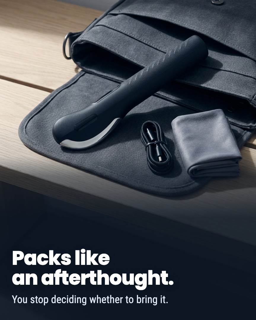 A handheld electronic device, charging cable, and cloth laid on the flap of an open grey canvas bag.
