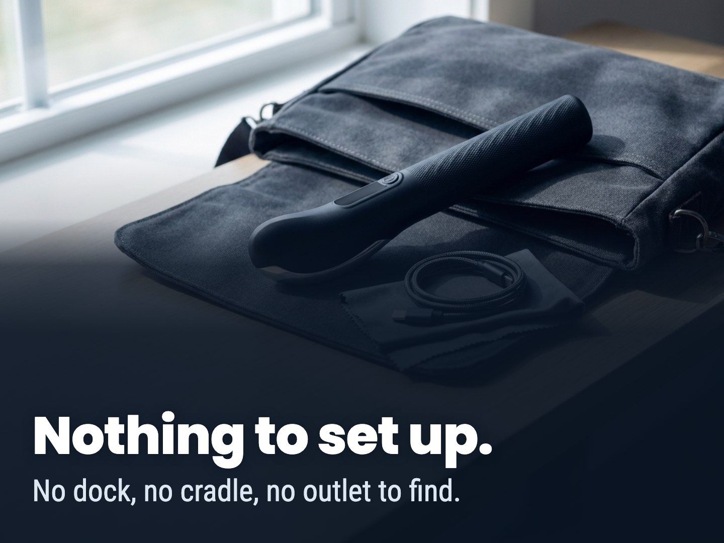 A black handheld device, its cable, and a cloth laid out on a grey canvas bag.