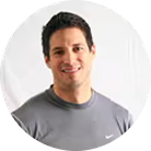 A circular headshot of a smiling man with dark hair, wearing a grey t-shirt.