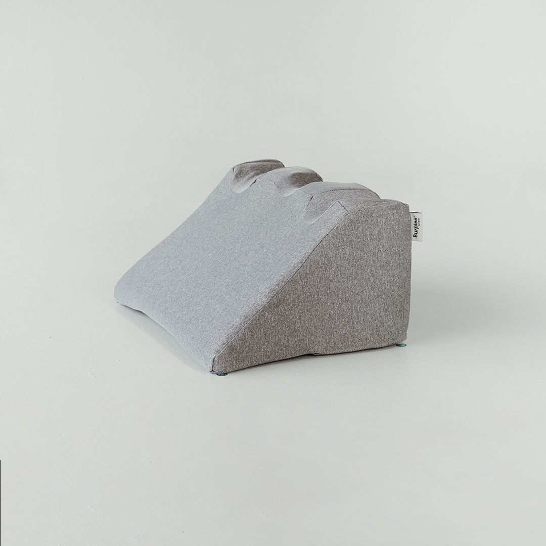 Gray, wedge-shaped cushion with a fabric texture on a white background.