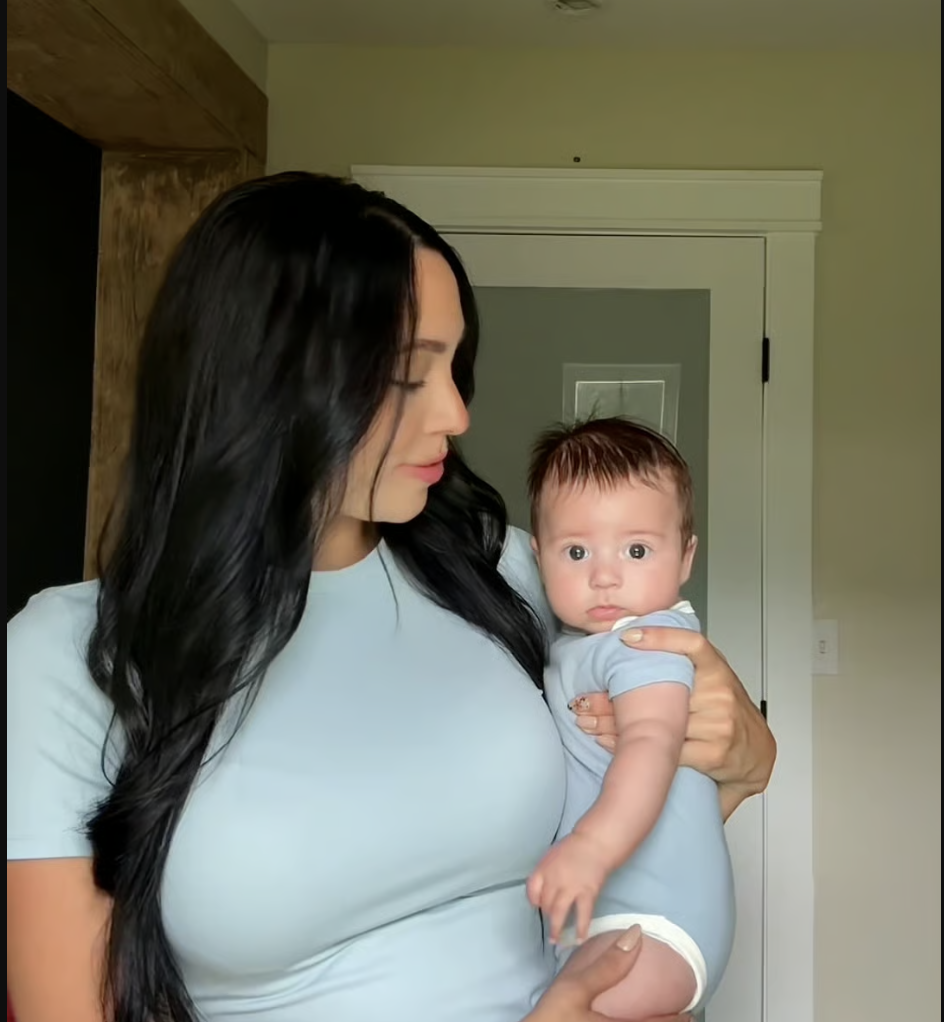 A man holding a baby, both smiling at their reflection in a mirror.