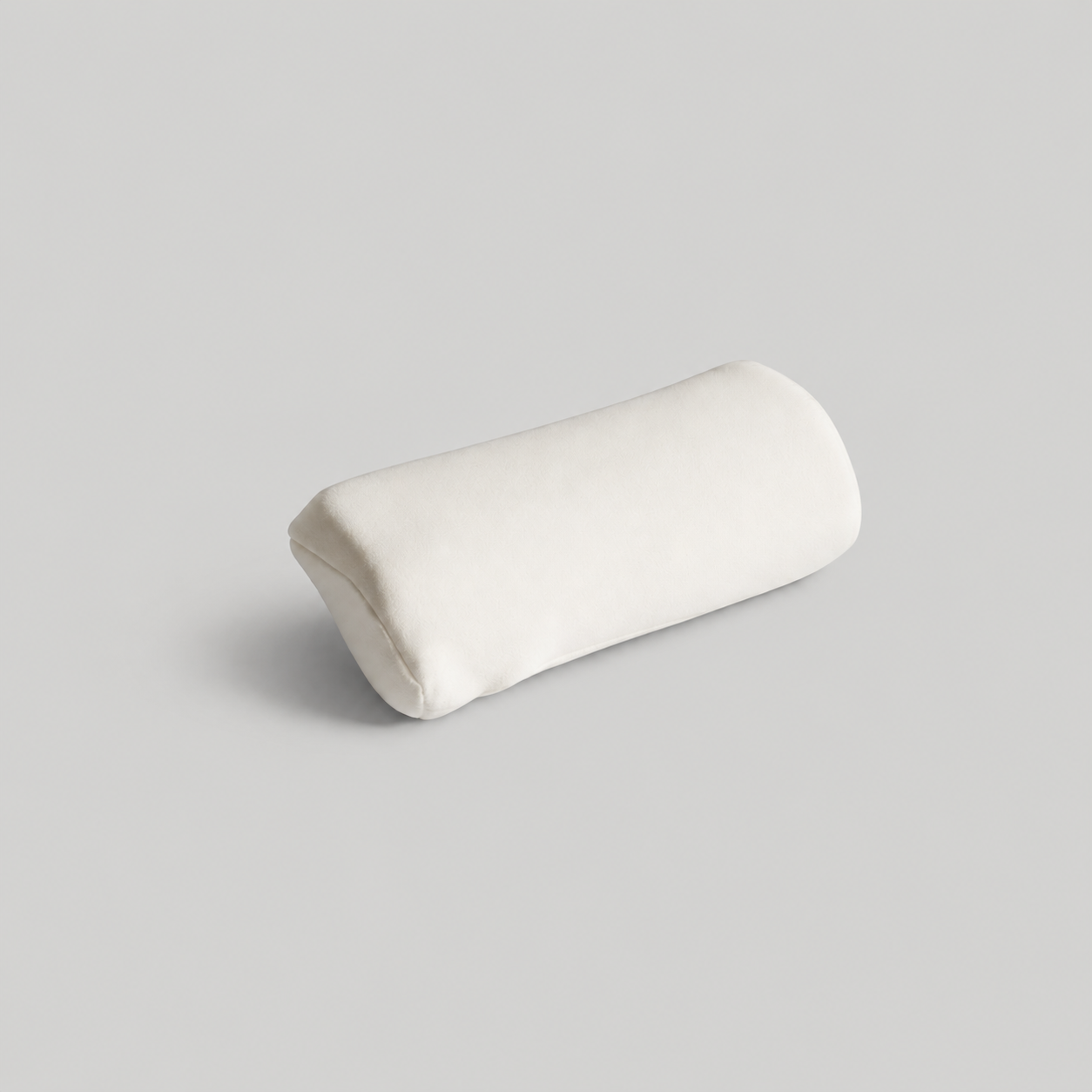 A small, white, cylindrical pillow resting on a plain, light gray background.