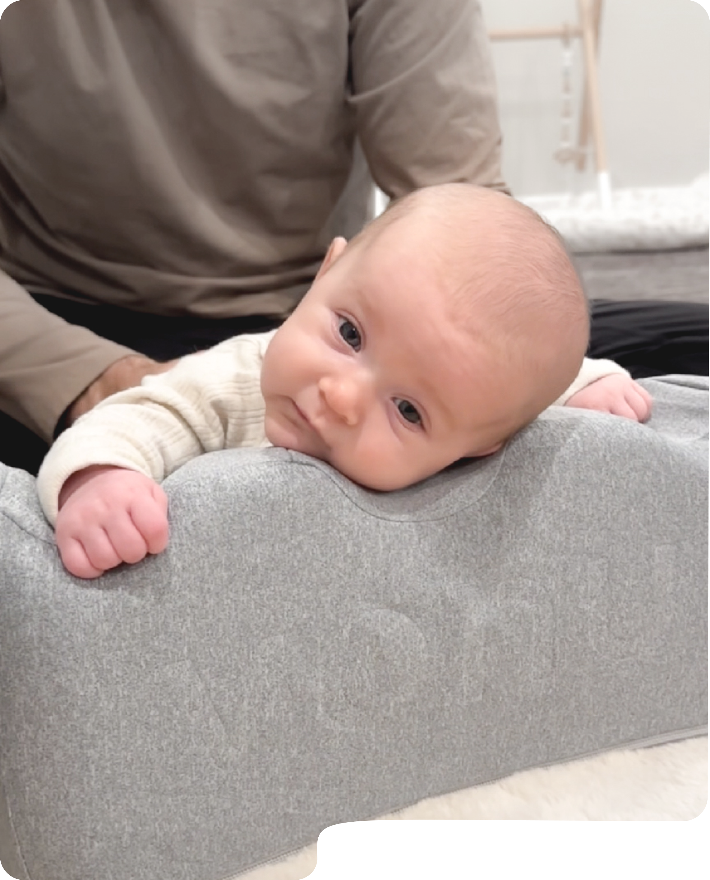 A mother smiles at her baby who is lying on a grey lounger, with a customer testimonial overlaid.