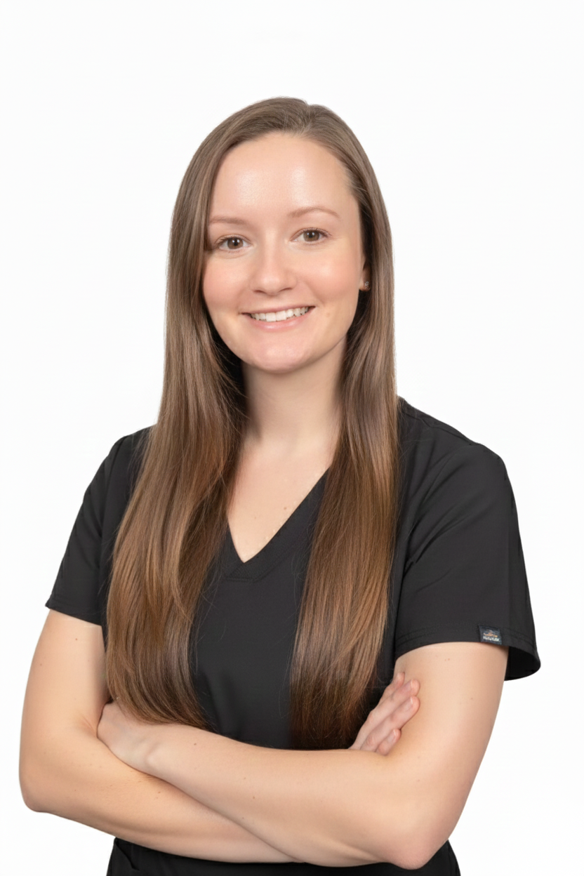 A smiling woman with long brown hair, wearing a black v-neck top, posing with her arms crossed.