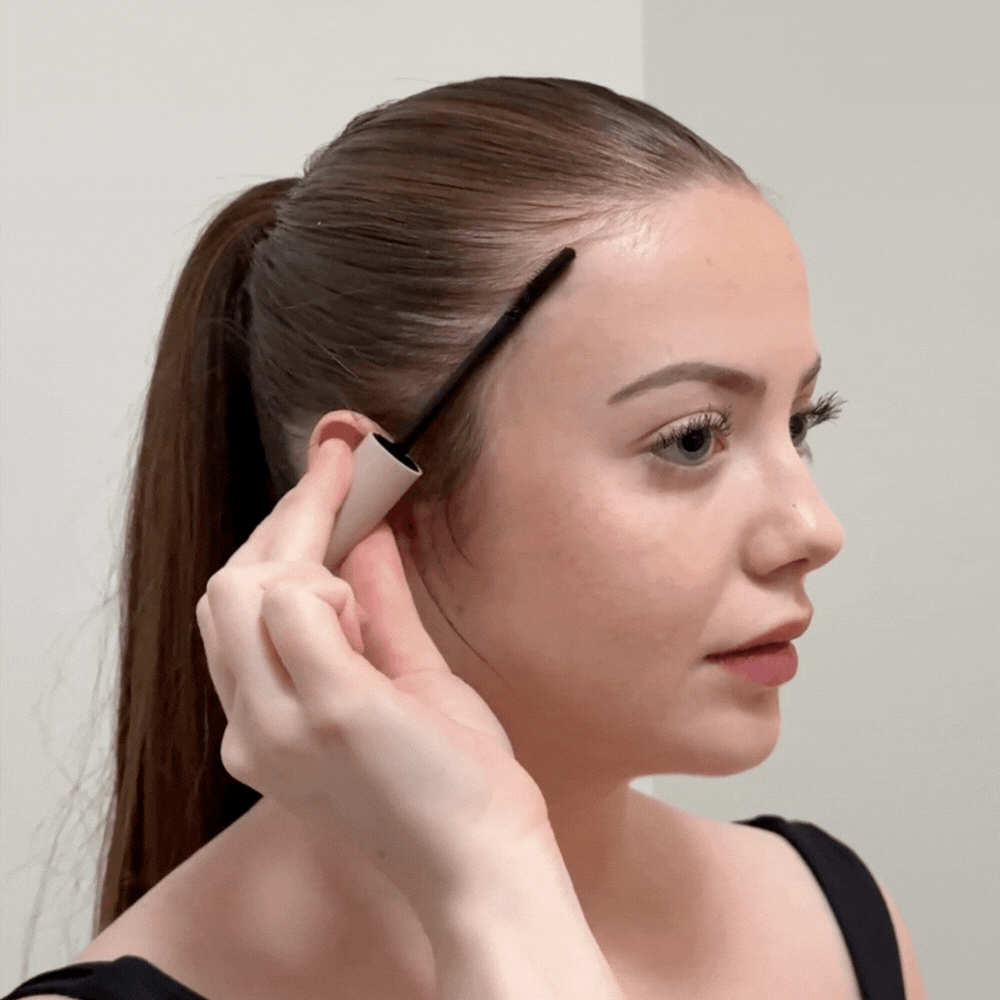 Person applying makeup with a brush to their hairline.