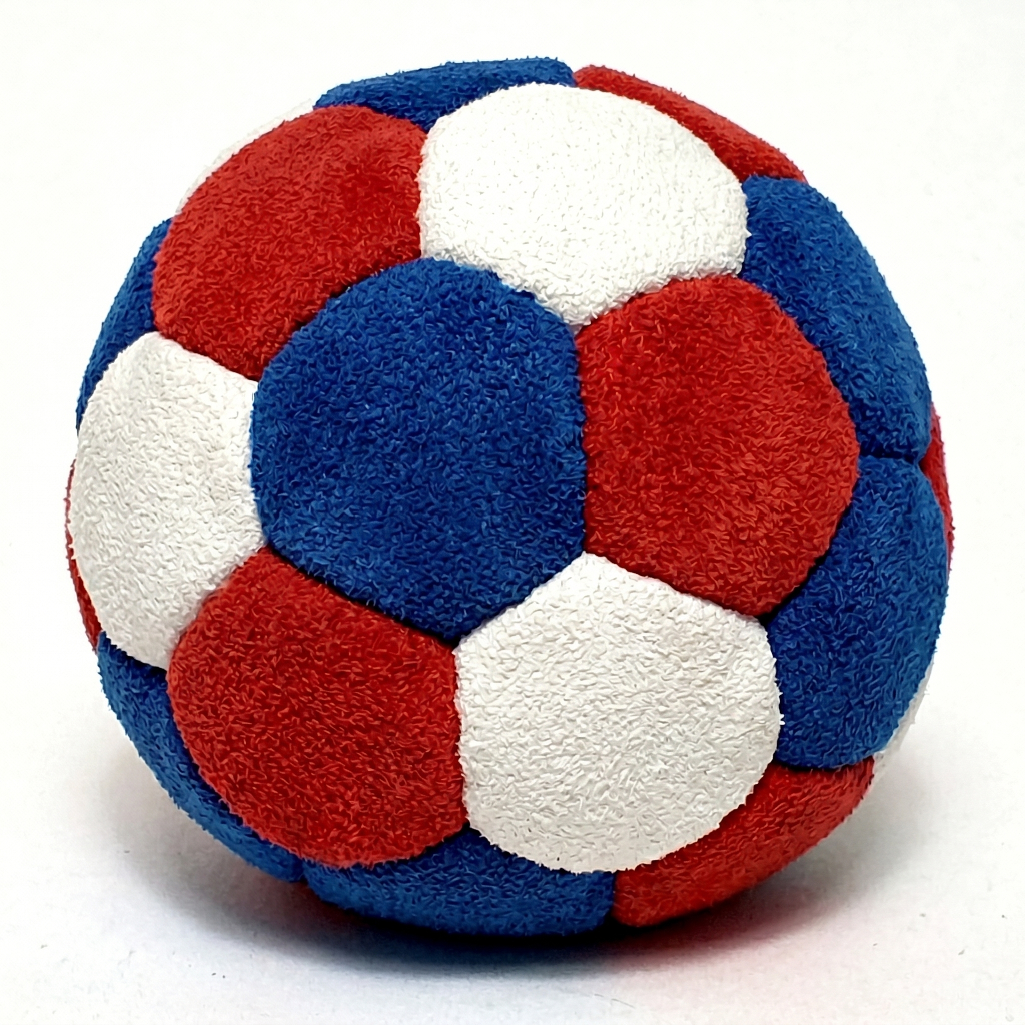 A plush, patched ball in red, white, and blue on a white background.