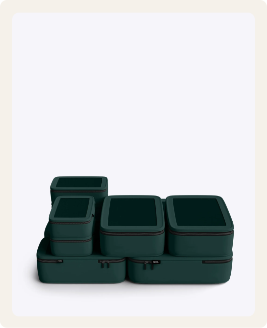A set of dark green packing cubes of various sizes stacked together on a white background.