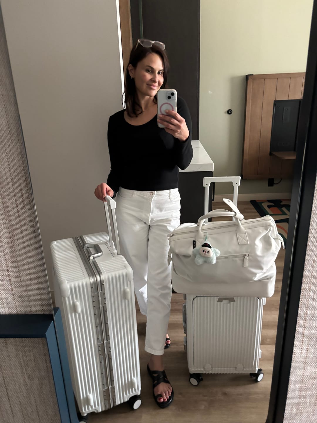 Woman with suitcase standing by open house door, ready to travel.