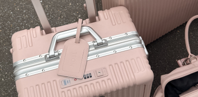 A close-up of a light pink, hard-shell suitcase with a matching luggage tag.