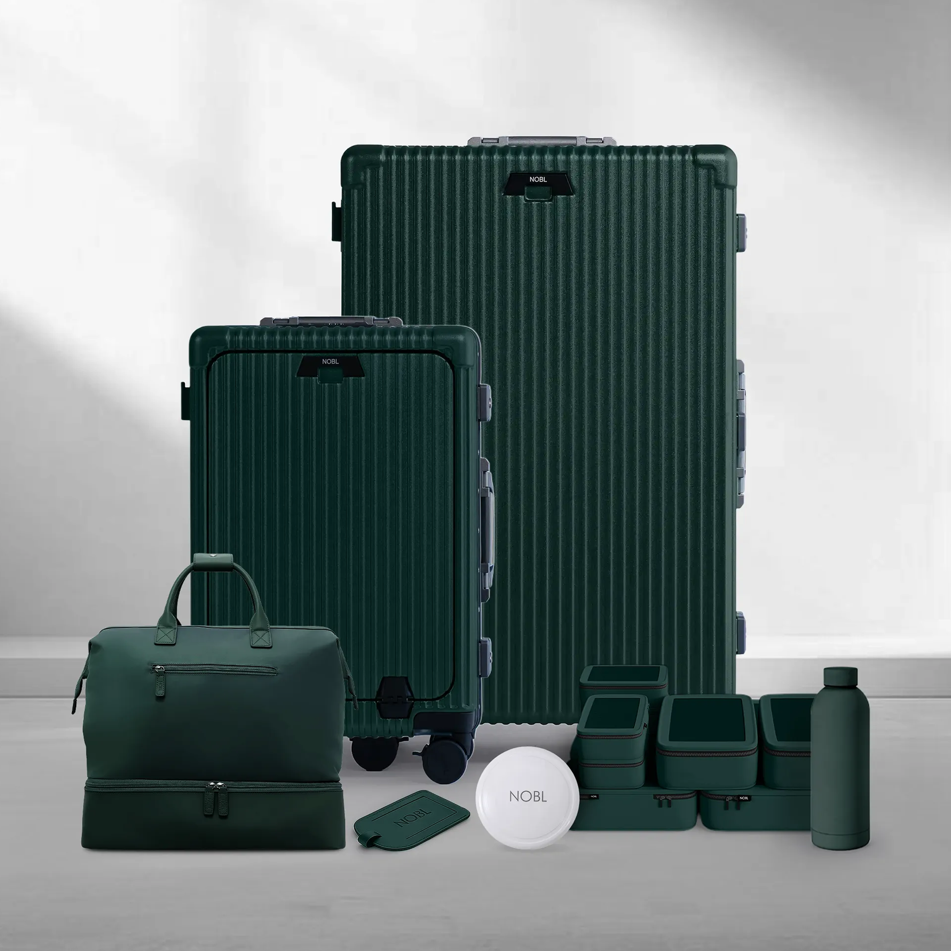A set of matching dark green luggage, including two ribbed suitcases, a duffel bag, and travel accessories.
