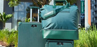 A set of green luggage, including two rolling suitcases and a duffel bag, sits outdoors.