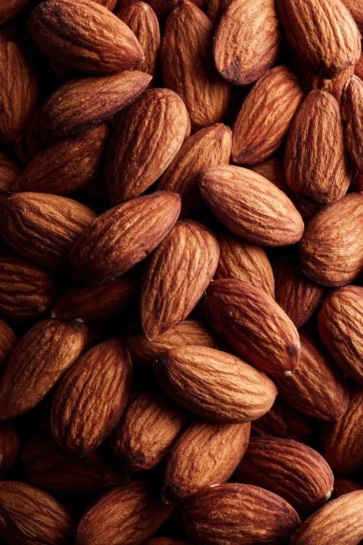 A close-up, top-down photograph of a pile of whole almonds.