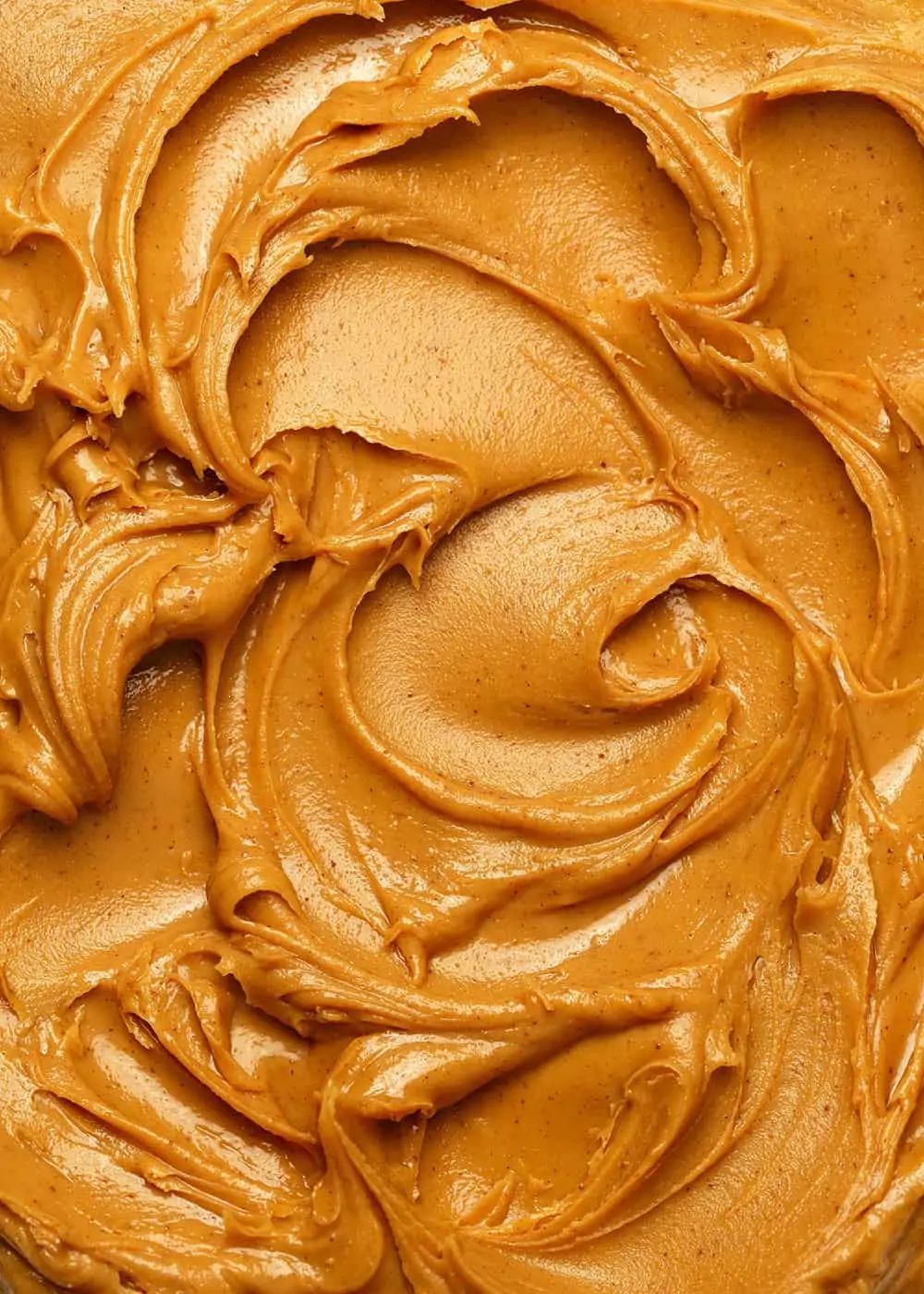 A close-up, top-down shot of creamy, swirled peanut butter.