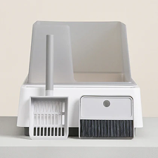 A white and grey high-sided litter box with a matching scoop and a small brush and dustpan set.