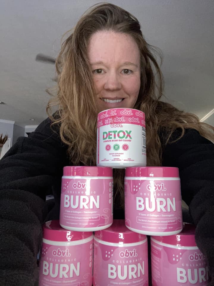 Person holding Obvi Detox and Burn supplement containers.