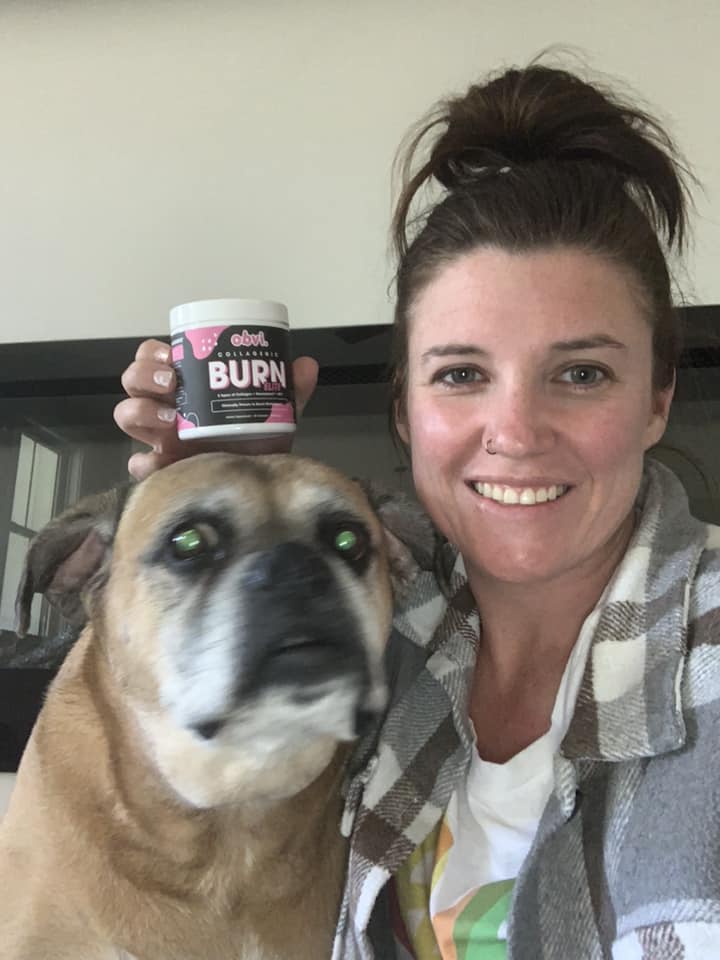Person smiling next to a dog, holding a jar labeled 'BURN.'